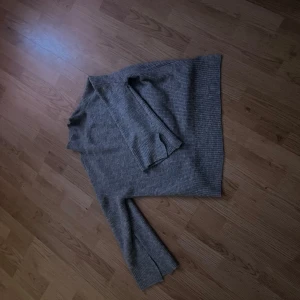 Grå ribbad polotröja - Säljer en stilren grå polotröja med ribbad struktur. Tröjan har långa ärmar och en klassisk polokrage, perfekt för kyligare dagar. Passar bra till både jeans och kjol.