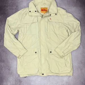 Beige jacka från Fjällräven - Säljer denna stiliga Field Jacket från Fjällräven för bara 1499kr! Pris kan diskuteras vid snabb affär!  ✨Specialfunktioner: Stora fickor på midjan (dubbelsidiga) och brösten. Ficka på höger arm. Ficka med kedja på insidan. Justerbar midja, vrist och även höften.   📐 Mått: Bredd under armhålorna 57 cm Jackans längd 79 cm Ärmlängd från hals 81 cm ♻️ Skick:  Underbar skick utan tecken på användning  🧵 Material: Yttermaterial 73% Polyamid, 27% Bomull Innermaterial 100% Polyester