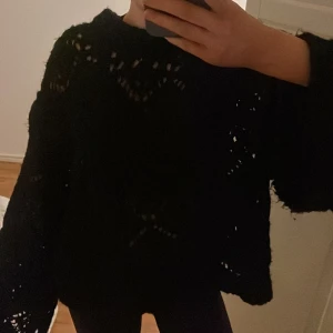 Svart stickad tröja från Zara - Säljer en svart stickad tröja från Zara med ett snyggt hålmönster. Tröjan har långa ärmar och en bekväm passform. Perfekt för kyliga dagar. 