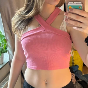 Rosa ribbad croppad topp - Säljer en rosa ribbad topp med korsade axelband. Toppen är croppad och har en tight passform, perfekt för sommaren. 