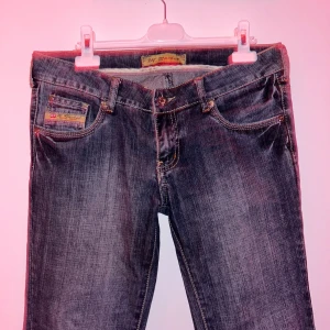 Mörkblå bootcut jeans - Snygga mörkblå lågmidjade bootcut jeans med dekorativa sömmar på bakfickorna. Klassisk femficksdesign och knappgylf. Perfekta för en avslappnad stil! 