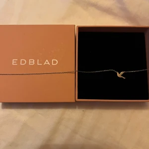 Halsband med fågelberlock från Edblad - Elegant halsband från Edblad med en fin fågelberlock i silver. Kedjan är tunn och smidig, vilket ger ett stilrent intryck. Perfekt för att lägga till en subtil touch av elegans till din outfit.
