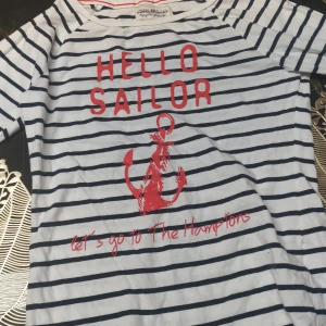 Randig tröja från Hampton Republic - Säljer en vit och marinblå randig tröja från Hampton Republic med texten 'HELLO SAILOR' och ett rött ankare på framsidan. Tröjan har långa ärmar och en avslappnad stil. Perfekt för en maritim look! 🛥️