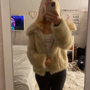 Beige pälsjacka - Säljer en fluffig och stilren beige pälsjacka med långa ärmar och en stor krage. Jackan har en mjuk och lyxig känsla, perfekt för att hålla sig varm och trendig. Den är enkel att matcha med olika outfits och ger en elegant touch. Pris går att diskutera 