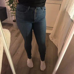 Levi’s Mile High Super Skinny - Snygga blå jeans med hög midja och tight passform. De har en klassisk femficksdesign och dragkedja fram. Perfekta för en stilren look. Sömmen har släppt lite på bakfickan, visar vid intresse.