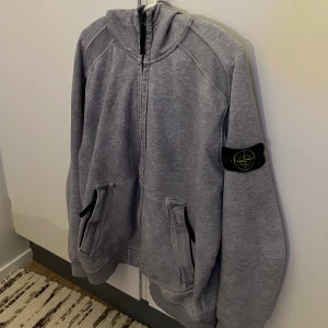  Stone Island hoodie (Special Collection)  - Säljer en stilren grå hoodie från Stone Island med dragkedja och huva. Perfekt för en avslappnad stil. Special Collection!! 