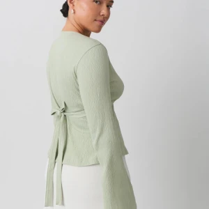 Tie topp från Gina tricot  - Snygg grön omlottopp från Gina tricot med lång ärm och knytning i ryggen. Toppen har en v-ringad design.