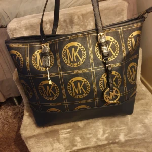 Michael kors väska - Helt ny axelbandsväska från Michael Kors. Väskan är marinblå med guldigt mönster. Fått i present så kan inte svara på äktheten. Mått 42×29. Se bilder💗