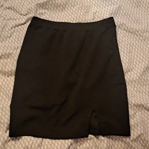 Svart kjol med slits - Snygg svart kjol med en liten slits framtill. Perfekt för en stilren look. Enkel design som passar till många olika toppar och skor.