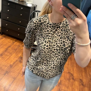 Leopardmönstrad t shirt - Snygg leopardmönstrad topp med trekvartsärm. Perfekt för att ge en trendig touch till din outfit. Toppen har en rund hals och är tillverkad i ett mjukt material. Helt ny från lager 157