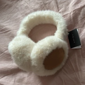 Vita pälsöronmuffar från Amisu, new yorker  - Säljer ett par fluffiga vita öronmuffar från Amisu. De är gjorda av mjuk päls och har en stilren design som passar perfekt för kalla dagar. Ett måste för vintern! Aldrig använda 