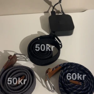 Tre flätade bälten med spännen - Säljer tre snygga flätade bälten i olika färger. Ett grått, ett blått och ett svart bälte, alla med silverfärgade spännen och bruna läderdetaljer vid spännet.