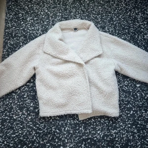 Beige teddyjacka från Gina Tricot - Mysig beige teddyjacka från Gina Tricot i storlek XL. Jackan har en klassisk krage och är perfekt för kyligare dagar. Den är långärmad och har en mjuk, fluffig textur som ger en trendig look.