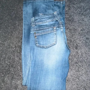 Blå bootcut jeans från Only - Snygga blå bootcut jeans från Only med låg midja. De har en klassisk femficksdesign och en lätt tvättad jeans look. Dem är i storlek W27 och L32