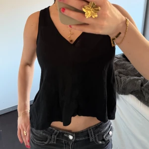 Svart ärmlös topp - Snygg svart ärmlös topp med v-ringning. Perfekt för en stilren look. Passar bra till både jeans och kjol.