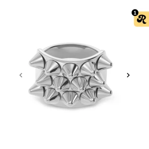 Silvrig ring med nitar - Cool och edgy silvrig ring med flera spetsiga nitar runtom från Edblad. Perfekt för att ge din outfit en tuffare look. Ringen har en bred design som verkligen sticker ut. Jätte bra skick💕