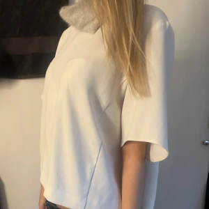 Vit finare T-shirt - Säljer en stilren vit topp med korta ärmar. Perfekt för en elegant look. Toppen har en lös passform och är tillverkad i ett mjukt material. Storlek S från someday.