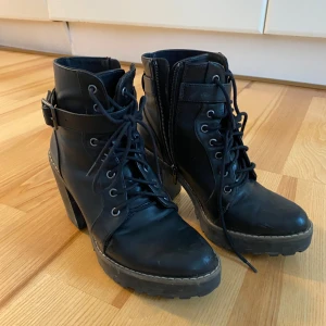Svarta högklackade boots  - Snygga svarta boots med klack och snörning. De har en dragkedja på sidan för enkel på- och avtagning. Strl 38. Smutsiga och kan behöva rengöras annars är skicket fint! 