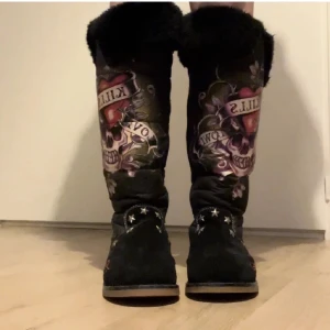 Ed Hardy skor - As coola ed Hardy skor (väldigt lika Uggs) första två bilderna är från en annan säljare men är samma passform och samma model i olika ljus (för de som vill se dom på) de sista 3 bilderna är de som säljs (helt nyskick kanske använd en gång men i sprillans ny skick perfekta till höst o vinter då de är värma på insidan och har fluffig päls och vikbara däruppe om man vill ha de framme eller om man vill ha dom längre ursnygga rare boots🥀☠️