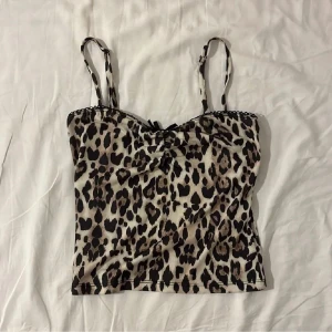 Leopardmönstrad topp - säljer ett snyggt leopardmönstrat linne med smala axelband och en liten rosett framtill från Gina Tricot. oanvänt men utan prislappen kvar i storlek xs. 🐆🐆