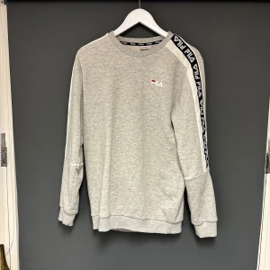 Grå sweatshirt från Fila - Grå mysig sweatshirt/tröja från Fila i storlek M. Den är använd men fortfarande i bra skick. Inga defekter. 
