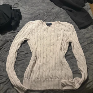 Rosa tröja Polo Ralph Lauren - Kabelstickad rosa tröja från Polo Ralph Lauren i mjuk pima bomull. Klassisk rund halsringning, långärmad och med ribbade muddar. Slim passform som sitter snyggt och stilrent. Perfekt för lager-på-lager under höst och vinter.