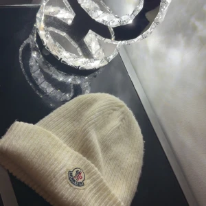 Mössa - Snygg vit mössa från Moncler med ribbad struktur och klassisk uppvikt kant. Mössan har Moncler-logga framtill och är tillverkad i mjuk ull som håller dig varm. Perfekt accessoar för kyliga dagar och en clean look.