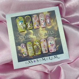 KittyCats (S);Medium Square - Handgjorda press-on naglar i pastellgul och ljusrosa med 3D-dekorationer, glitter, söta katter, kaniner, rosetter och små frukter. Naglarna har en glansig finish och detaljer i lila, vitt och silver. Perfekt för dig som vill ha unika och lekfulla naglar. I storlek S: 15 mm, 11,5 mm, 12 mm, 11 mm, 9 mm 