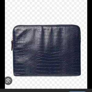 Mörkblå datorfodral i skinn - Snygg mörkblå datorväska med croco-mönstrad yta i skinnimitation. Väskan har dragkedja på sidan och stilren, minimalistisk design som passar perfekt till plugget eller jobbet. Aldrig Andvänd 
