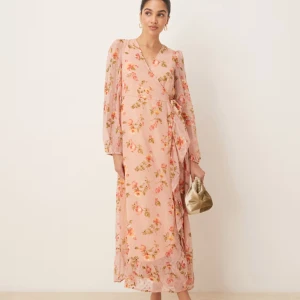 Blommig omlottklänning från Vila - Superfin långklänning från Vila i ljusrosa med blommigt mönster. Klänningen har omlottmodell med knyt i midjan, volangdetaljer längs nederkanten och långa ärmar. Helt ny med prislappar kvar! 