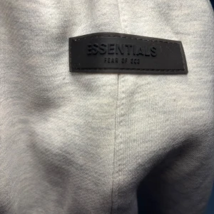 Ljus grå Essentials Fear of God byxa - Snygg ljusgrå mjukisbyxor från Essentials Fear of God med svart logga på och den är bekväm att ha på sig.