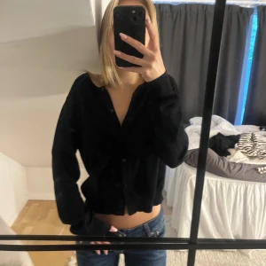 Svart kofta från Monki - En svart, klassisk kofta från Monki med rund halsringning och knappar framtill. Modellen är lite croppad och har långa ärmar! Passar till allt 💗