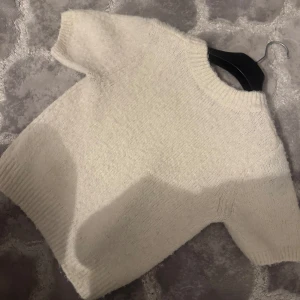 Vit stickad tröja från Gina Tricot - Supermjuk och fluffig vit stickad tröja från Gina Tricot. Tröjan har korta ärmar, rund halsringning och ribbade muddar. Storlek S men passar även till xs