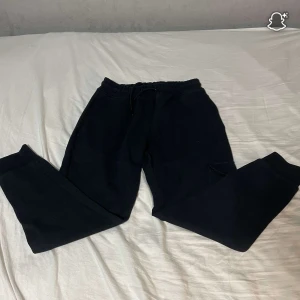 Mörk blå mjukisbyxor Stone Island  - Mörk blå mjukisbyxor från Stone Island i storlek M. Byxorna har resår och snörning i midjan, muddar vid bensluten och sidofickor. Perfekta för chill dagar eller när du vill ha en avslappnad stil. Tyvärr ett hål i ett av sido fickorna men annars bra skick 