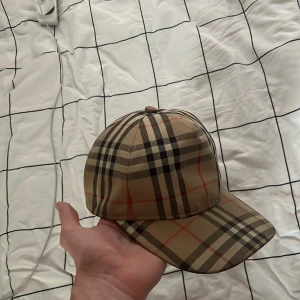Burberry keps - Säljer min burberry keps då den it passar mig längre. Den är väl använd men varsamt. Därför har den gått sönder lite där back ( se bild 5 ) men limmade de så den ser likadan ut som förr
