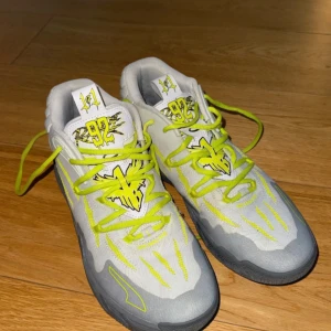 Puma MB.03 LaMelo Ball basketskor - Säljer ett par Puma MB.03 LaMelo Ball basketskor i grått och neon gul. Skorna har coola detaljer, broderade loggor och neon snören. Ovandelen är i syntetmaterial och mesh för bra andning. Kommer med originalkartong.