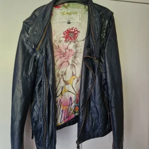 Mörkblå konstskinnjacka Desigual med broderi - Snygg mörkblå konstskinnjacka från Desigual med coola broderade detaljer och texten LOVE på ryggen. 