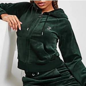 Mörkgrön velour kofta med huva och byxa - Säljer både koftan och byxorna för används ej. Användes bara några gånger. Dock har tappat några diamanter! Storlek XS på båda. Det står juicy på ryggen och på rumpan. Kom med bud gärna!