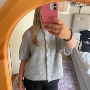 Grå stickad kofta  - Supermysig grå stickad kofta med korta ärmar och knappar. 💓💓Perfekt att slänga över en t-shirt eller linne för en chill look. Storlek M och sitter lite stort på mig som vanligtvis har S