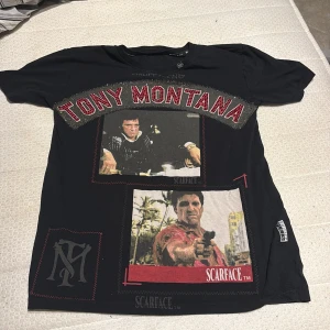 Svart Scarface t-shirt Philipp Plein - Svart t-shirt från Philipp Plein med stora Scarface-prints och texten 'Tony Montana' i röda paljetter framtill. Coola detaljer med glittrande stenar och PP-logga på ryggen. Rund hals och korta ärmar, tillverkad i mjuk bomull.