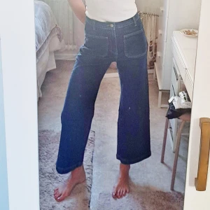 Front Pocket Jeans från NaKd - Säljer ett par mörkblå jeans med hög midja och breda ben. Jeansen har stora, synliga fickor fram och klassiska bakfickor. Snygg och trendig passform som ger en avslappnad vibe. Perfekta till sneakers eller boots. Det är storlek 36, så lite stora för mig i midjan. True to size. Jag är 1,72. 