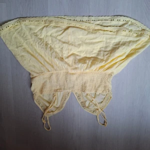 Gul blus med spetsdetaljer - Söt gul blus med tunna axelband och broderade spetsdetaljer längs kanterna. Toppen har en luftig passform och smockad midja som ger en feminin siluett. Perfekt för varma dagar och ger en romantisk vibe till din outfit. Fråga om mera bilder behövs. Säjet pga att den inte kommer till användning.