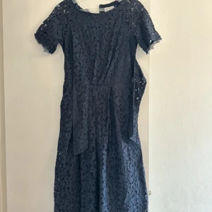 Mörkblå spetsklänning från Hollister - Supersnygg mörkblå långklänning från Hollister med korta ärmar och vackert spetsmönster över hela klänningen. Klänningen har rund halsringning och en feminin siluett som ger en elegant vibe. Perfekt för dig som vill sticka ut med stil!