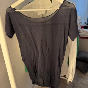 Svart tunn kortärmad topp - En svart, tunn och lätt topp med korta ärmar och rund halsringning. Modellen är enkel och stilren, perfekt att matcha med olika outfits. Materialet är tunt och ger en luftig känsla, toppen har en rak passform.