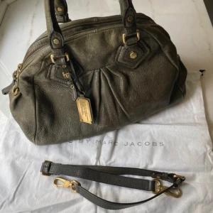 skinnväska Marc by Marc Jacobs - Säljer en snygg handväska i äkta skinn från Marc by Marc Jacobs. Väskan har guldfärgade metalldetaljer, dubbla handtag och avtagbar axelrem. 