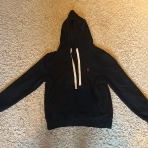 Marinblå hoodie från Ralph Lauren - Hej, säljer nu min marinblåa ralph lauren hoodie då jag inte använder den längre, en lite defekt se sista bild. [Skick: 8/10] [Nypris:1999:-] [Mitt pris: 499] Hör av er vid frågor och funderingar. 