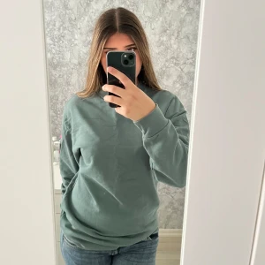Grön crewneck sweatshirt i bomull - Säljer en stilren grön sweatshirt med rund hals och långa ärmar. Tröjan är i mjuk bomull och har en relaxed passform, perfekt till jeans eller joggers. Enkel och clean look utan tryck eller mönster. Vid frågor hör av dig!