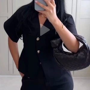 Svart blus med guldknappar från Zara - Stilren svart blus från Zara med korta vida ärmar och två snygga guldknappar framtill. Blusen har v-ringning och rak passform, perfekt till både jeans och kostymbyxor. Oanvänd!