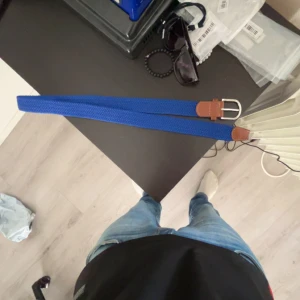 Onewear bälte - Snyggt blått bälte med silverfärgat spänne och bruna skinn-detaljer vid ändarna. Bältet har en stilren och enkel design som passar till jeans eller chinos. Perfekt accessoar för att lyfta din outfit.