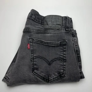 Levi's 501 grå jeans - Snygga grå Levi's 501 jeans med klassisk femficksdesign och ikonisk röd Levi's-tag på bakfickan. Jeansen har en rak passform och är tillverkade i slitstarkt denimtyg. Perfekta för en avslappnad och cool stil.
